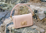 Una borsa rosa con un fiocco dorato sopra