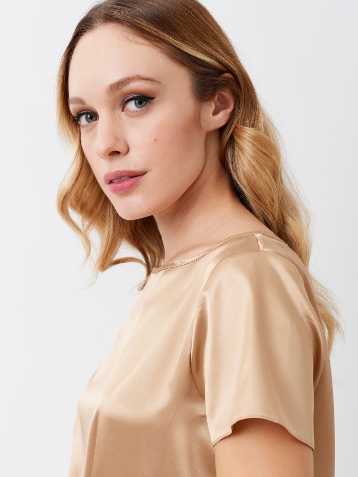 T-Shirt en satin couleur beige Blouse, modèle t-shirt boxy, à lignes épurées, en satin léger. Le t-shirt se portera facilement sous une veste ou pour donner une touche étincelante à vos looks de jour. Le mannequin mesure 1,76 m et porte une taille S. Ce vêtement a été entièrement fabriqué en Italie.  Rinascimento
