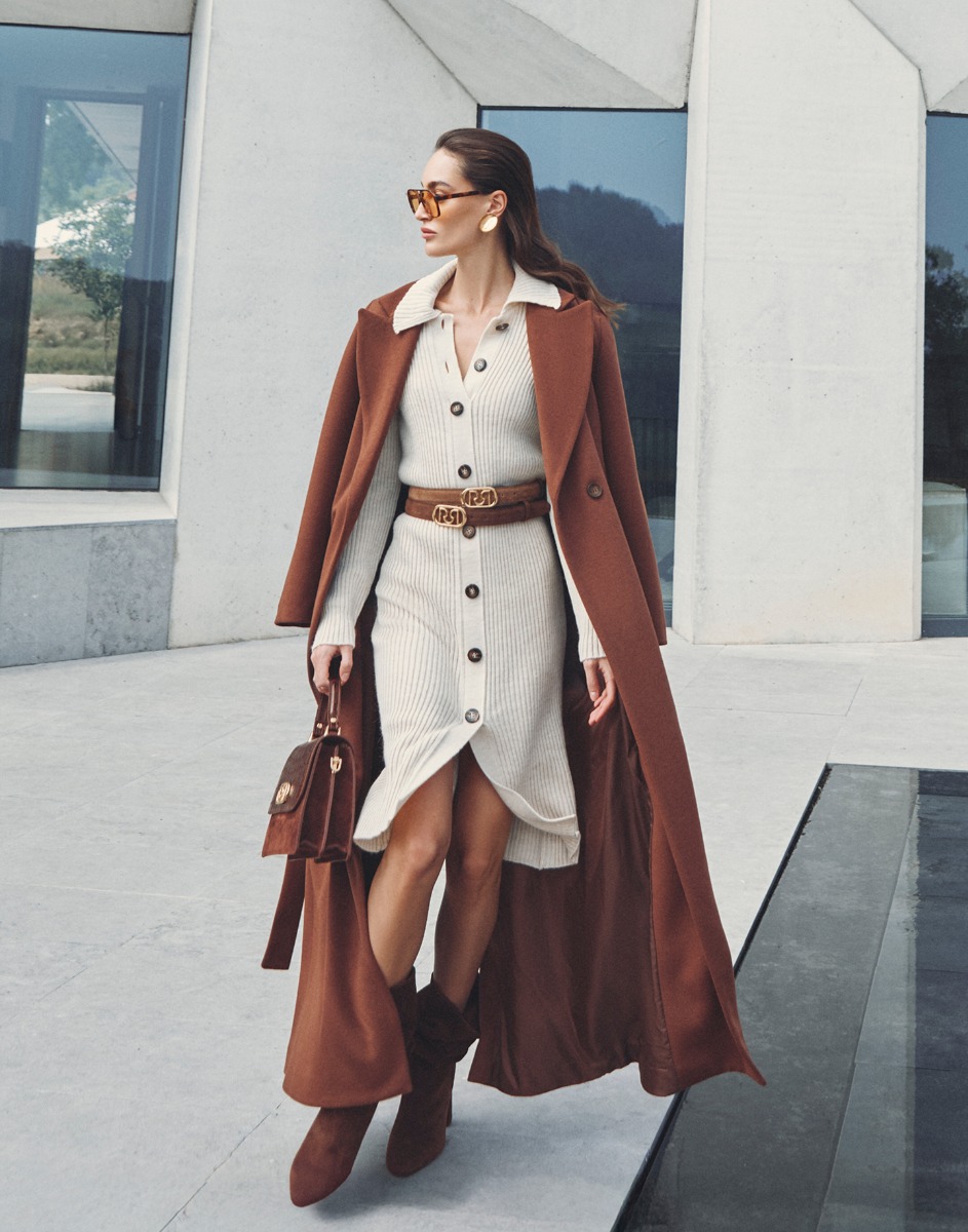 Donna in un cappotto marrone e vestito che cammina all'aperto