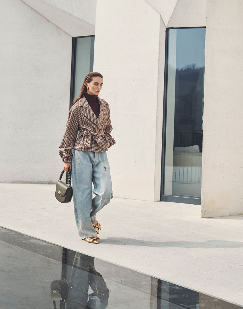 Donna in un cappotto marrone e vestito che cammina all'aperto
