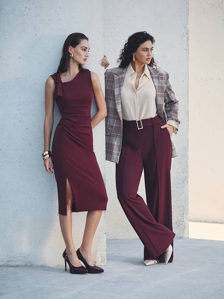 Due donne vestite di bordeaux si trovano fianco a fianco, con espressioni amichevoli