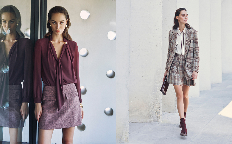 Donna in blusa e gonna viola, sorridente, in un ambiente luminoso