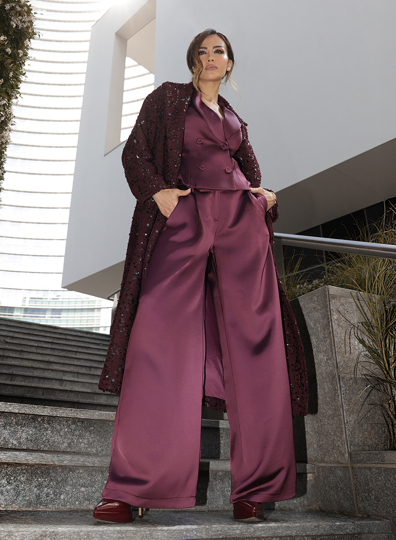 Giorgia Palmas in pantaloni e cappotto bordeaux, in piedi su una scalinata